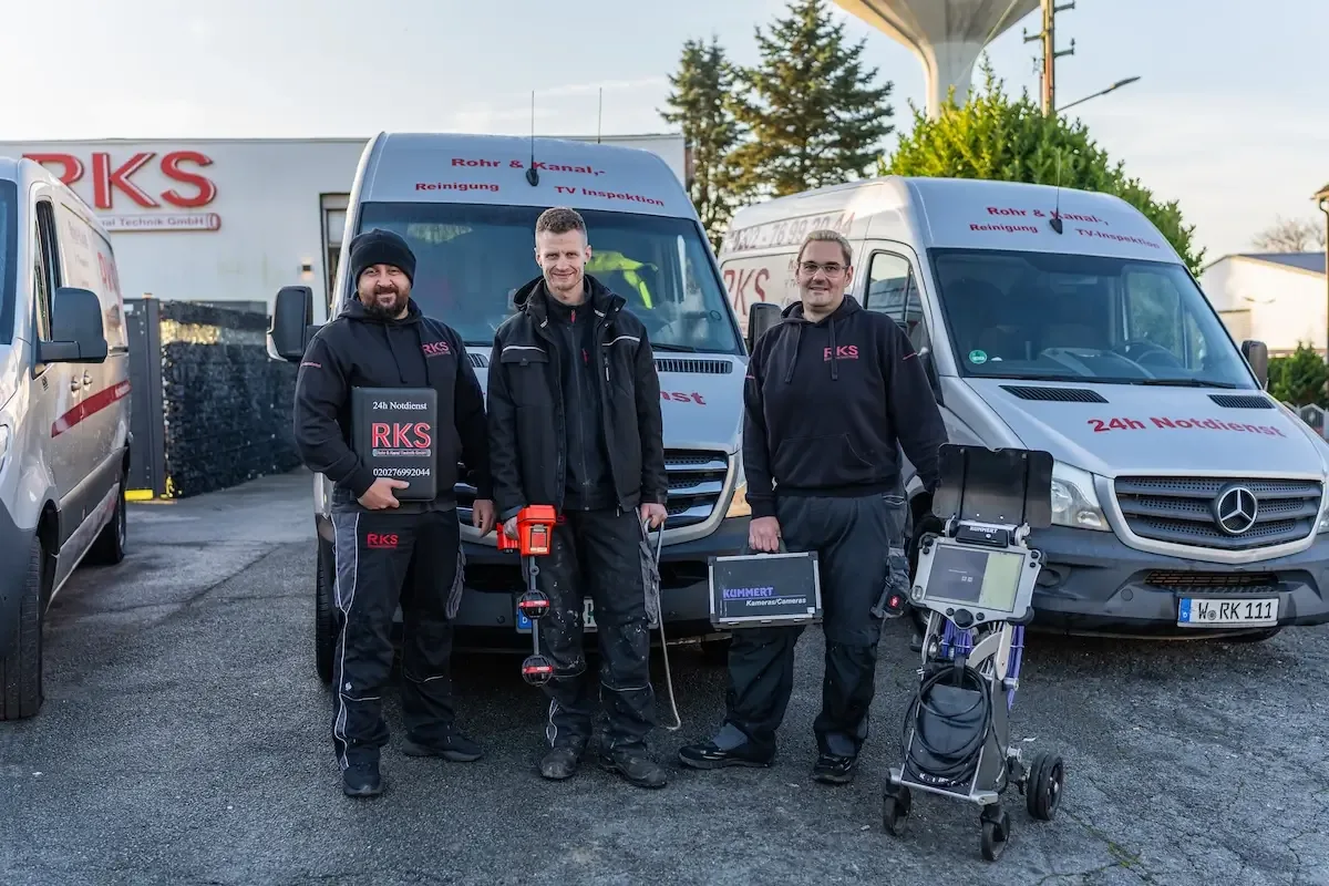 Ein komplettes Monteur-Team steht vor den Servicefahrzeugen des Betriebs