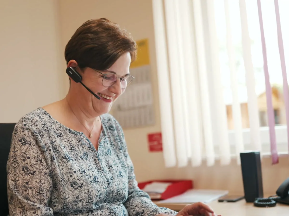 Eine Mitarbeiterin mit Headset arbeitet am Rechner