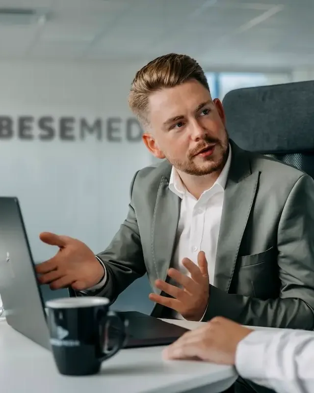 Erich Bese erklärt einem Kollegen am Laptop das Konzept für einen Partnerbetrieb